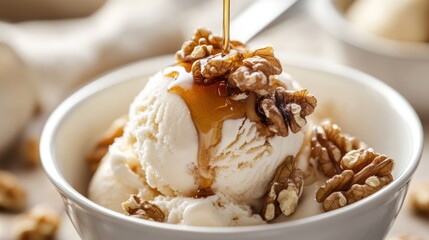 A scoop of vanilla ice cream topped with chopped walnuts and a drizzle of caramel sauce in a white bowl.