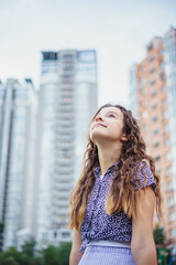Pretty girl in casual clothes against the background of a metropolis street and a skyscraper. View from below