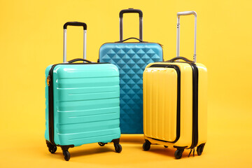 Three different bright suitcases on yellow background