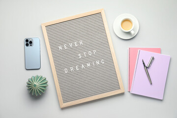 Flat lay composition of letter board with phrase Never Stop Dreaming on light table