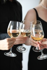 People clinking glasses of wine indoors, closeup