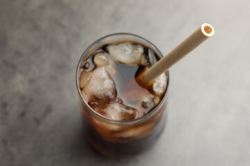 Tasty refreshing drink with straw in glass on grey table, above view