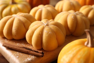 Raw pumpkin shaped buns and ingredients on wooden table, closeup
