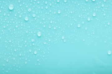 Water drops on turquoise background, top view