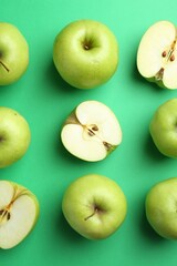 Flat lay composition with whole and cut apples on green background