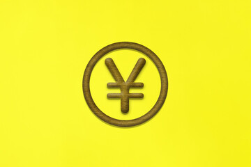 茶色いお金の円マークの木製アイコンが中心にある黄色い背景