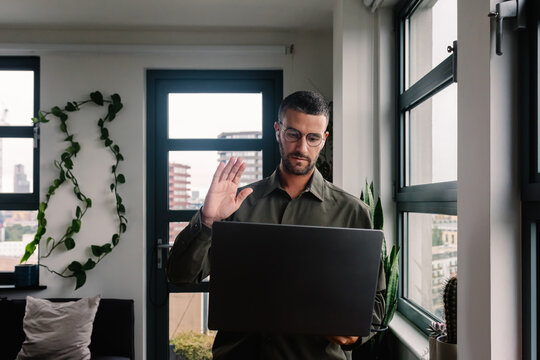Businessman greets his computer camera during a virtual meeting