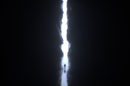 Man coming out of a large cave or passageway with a beam of light.