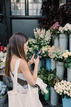Vacationer uses her mobile phone to take a photo of flower arrangement