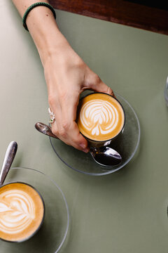Hands of an anonymous lady holding a cup of cappuccino coffee