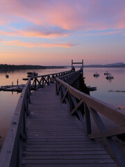 Fototapeta premium Pink Sunset at Old Hancock Point Pier Tranquil Scene with Water and Boats and Dock Leading to Water