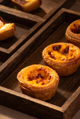 Sunlight shining on egg tarts, wooden dining table and tableware indoors
