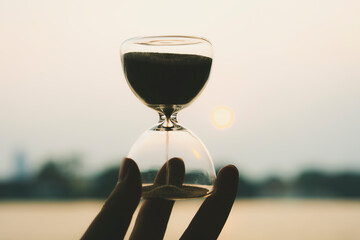 Hand holding the hour glass with bokeh of sea background. time to relax and summer concepts.