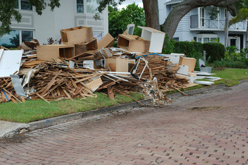 Large piles of trash, furniture, household items stacked on side of a brick street curb. After a...
