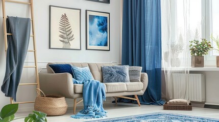 Blue curtain, posters and carpet in living room with blankets on ladder next to sofa with pillows