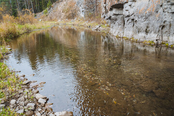 A beautiful, winding river flows gracefully through a picturesque landscape, which is adorned with majestic rocks and vibrant green grass, all nestled within a serene and enchanting forest