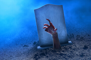 Zombie hand rising out from the grave tombstone with fog, Halloween theme