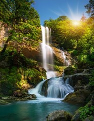 Obraz premium Crystal Clear Waterfall Cascading Down a Rocky Cliffside, Surrounded by Lush Green Trees and Vibrant Flora, Bathed in the Soft Light of Early Morning Sunshine