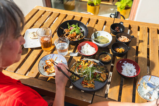 People Dining on Outdoor Terrace with Asian Food