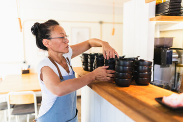 Korean Business Owner Organizing Plates by Counter Before Opening