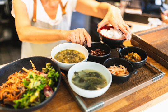 Korean Chef Finalizing Plates for Service Behind Counter