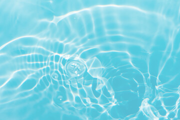 Blue water with ripples on the surface. Defocus blurred transparent blue colored clear calm water surface texture with splashes and bubbles. Water waves with shining pattern texture background.