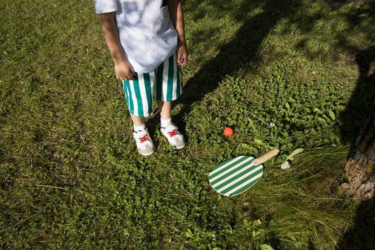 Child playing with a red ball and racket outdoors