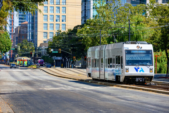 VTA light rail train travels along San Carlos Street in downtown San Jose surrounded by green trees and urban scenery - San Jose, California, USA - September 15, 2024