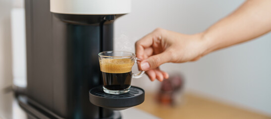 Espresso cup with steam and froth during Coffee making Coffee by Coffee Maker Machine on wood table bar. Cafe shop, Daily beverage drink at Home, Apartment and Office concept