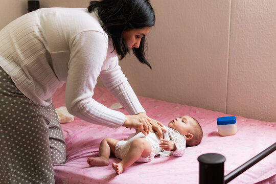 Young mother changing her baby's diaper.