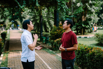 Two Southeast Asian men engaged in a lively conversation at a city square.