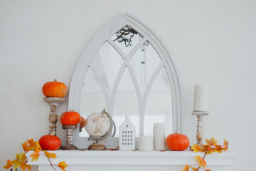 A cozy autumn mantel decorated with pumpkins and a vintage globe in a bright room