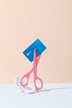 Scissors Cutting Credit Card and Receipt Against Pastel Background