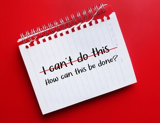 Notebook on red background with handwriting I CAN'T DO THIS, changed to HOW CAN THIS BE DONE? - to...