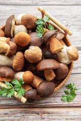 A vibrant assortment of fresh mushrooms and herbs in a woven basket on a rustic wooden table