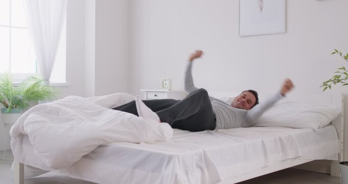 Happy morning active wake up, man awaken enjoys after healthy sleep on comfortable bed, white soft clean pillow, orthopedic mattress, enough sleeping, greeting new day, full of energy positive start