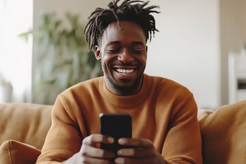 Happy Man With Dreadlocks Sitting On A Couch Using His Phone