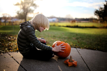 Young Boy Child Carving Pumpkin at House on Halloween in Fall