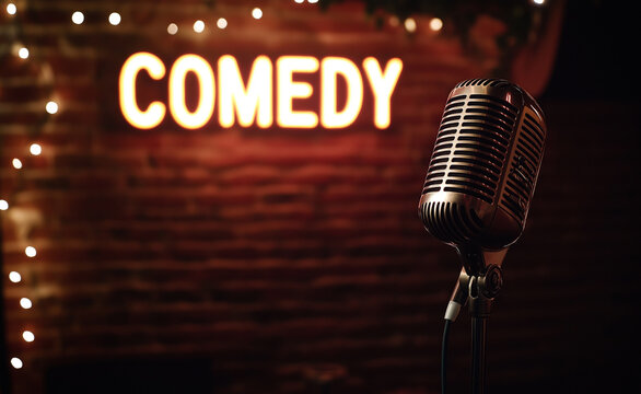 Microphone on stage with a neon comedy sign in the background.