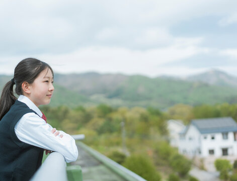 学校の屋上から景色を眺める女子生徒