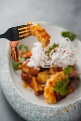 Fried Shrimp on a Fork with a Plate of Fried Shrimp in the Background