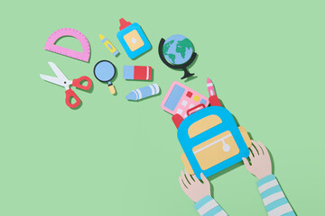 The child's hands holding a blue backpack filled with school supplies