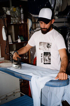 Man Ironing Clothes In His Laundry Business. Flash Film Photography.