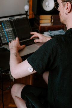 A man working in home studio while wearing health monitoring device 