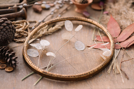 Circular frame with dried plants and pinecones on table