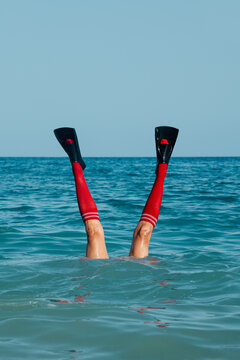 man wearing socks and swimfins upside-down into the ocean