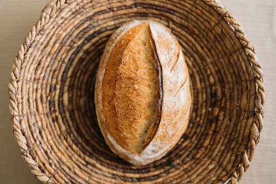 Single rustic loaf of bread in round wicker basket bread