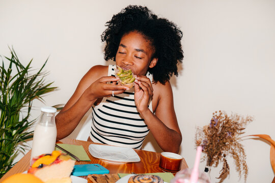 Black woman eating avocado toast for breakfast