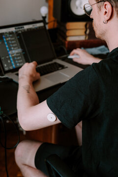 A man working in home studio while wearing health monitoring device 
