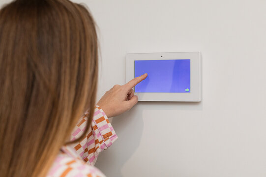 Person operating touchscreen device on wall indoors.